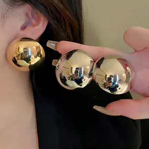 Polished oversized golden sphere hoop earrings featuring a mirrored metallic finish