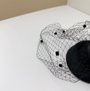 Detail of vintage black mesh fascinator hat with polka dots and feather accents
