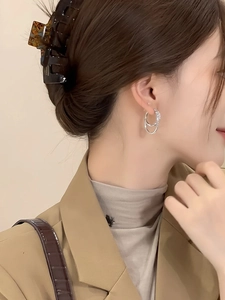 Close-up of elegant double-layered silver circle earrings worn by a model in beige suit