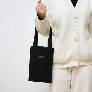 Detail of a mini black canvas tote bag featuring a Geometric Life label and handle
