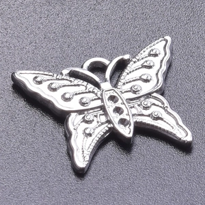 Macro shot of silver butterfly charm with textured wings and inlay details for jewelry