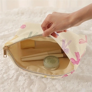 Beige corduroy makeup bag with colorful bow prints and golden zipper detail