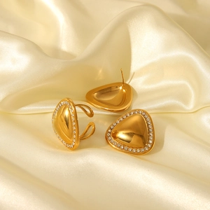 Detailed view of gold triangle jewelry set with crystals on beige silk fabric