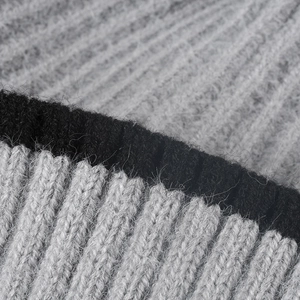 Thick color-block knit beanie with pompom showing ribbed wool texture and soft grey-black yarn