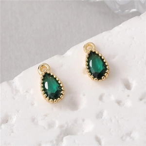 Detailed view of emerald waterdrop pendant with golden beaded edge and hanging loop