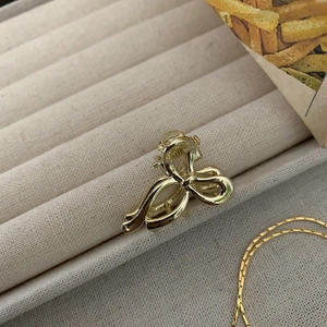 Dettaglio di una mini clip per capelli in metallo dorato a forma di fiocco su velluto