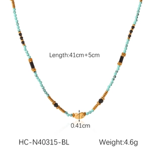 Close-up of turquoise and black beaded necklace with gold pendant on white background