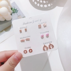 Detailed set of six pairs of rose gold stud earrings with pink pearls on a card