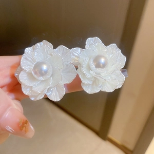 Detail view of elegant white flower earrings with pearl accent on silver needles