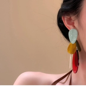 Detail view of Bohemian acrylic teardrop tassel earrings worn by a model in soft lighting