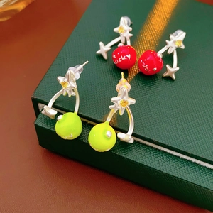 Macro detail of red and green cherry earrings with lucky lettering and silver stars