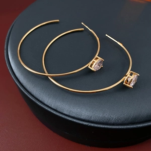 Détail macro d'une boucle d'oreille créole dorée avec poinçon S925 et zircon brillant