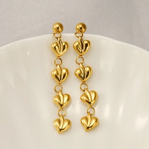 Détail de boucles d'oreilles cœur en acier inoxydable plaqué or 18k sur un bol blanc