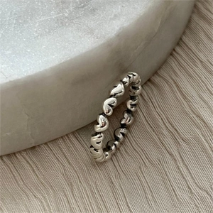 Elegant 925 sterling silver heart-shaped open ring on a grey stone pedestal