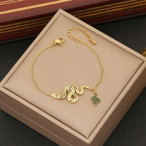Golden snake bracelet with star-moon patterns and green gemstone pendant on jewelry box