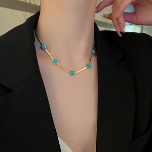 Bohemian gold snake chain necklace with five square turquoise stones on a model's collarbone