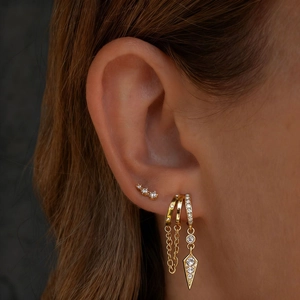 Gros plan de boucles d'oreilles dorées en acier inoxydable avec perles et cristaux