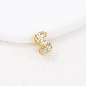 Macro shot of gold-plated letter S charm paved with sparkling cubic zirconia crystals