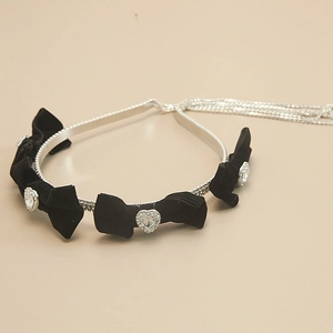 Velvet bow headband with heart crystals and silver chain tassels on beige background