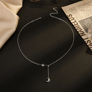 14K gold plated stainless steel necklace with moon and star pendants on black background