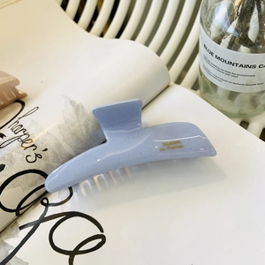 Sparkling light blue acetate hair claw clip with golden lettering on a magazine background