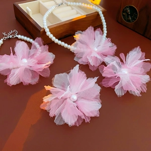 Close-up of pink fabric floral necklace with pearl centers and matching accessories