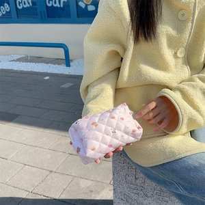 Pink quilted pouch with bear patterns shown in use against an outdoor street background