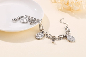 Detail of silver stainless steel double chain bracelet with sun and moon oval pendants