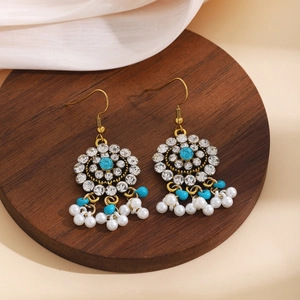 Macro detail of bohemian floral earrings with white pearls and blue bead tassels