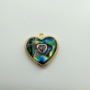 Dettaglio macro di un ciondolo a cuore placcato oro 18K con conchiglia abalone e gemma