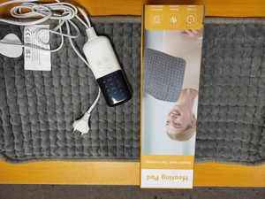 Detail view of electric heating pad with digital controller on wooden desk surface