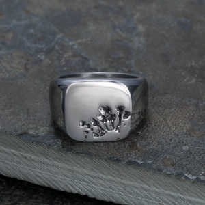 Polierter Edelstahlring im Punk-Stil mit Lava-Textur auf grauem Natursteinhintergrund
