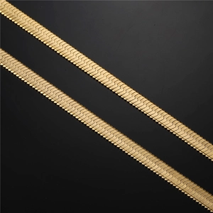 Macro shot of two golden flat snake bone chains with metallic texture and reflection