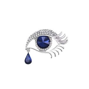 Evil eye brooch with silver metal base, white crystals and dark blue teardrop pendant
