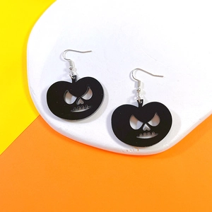 Detail of black acrylic pumpkin earrings on a white display tray for Halloween fashion