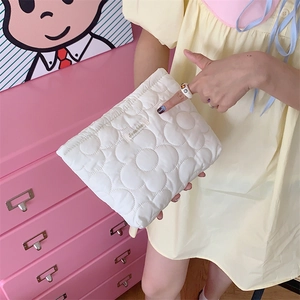 Close-up of white quilted flower texture toiletry bag held by a person in a soft setting