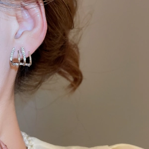 Close-up of double-layer silver-tone C-shaped stud earrings with sparkling pavé zircon stones