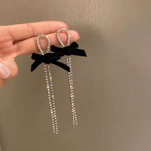 Gros plan de boucles d'oreilles argentées avec nœuds en velours noir et strass brillants