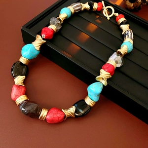 Close-up of vintage multi-color beaded necklace with golden metal spacers on black tray