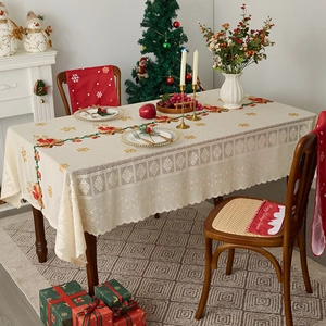 Close-up of festive beige lace tablecloth with Christmas holly and bell embroidery details