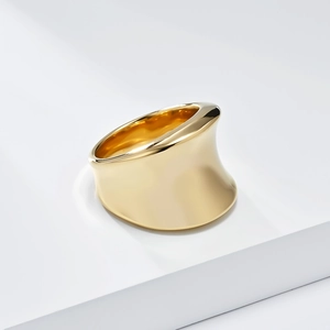 Macro view of wide gold-plated sculptural ring featuring a polished mirror-finish surface