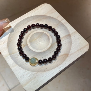 Detail of red garnet beaded bracelet featuring a gold-wrapped green jade center stone