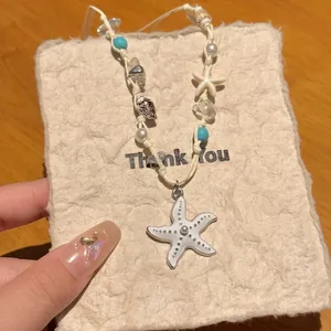Close-up of summer seashell necklace with white starfish pendant and turquoise beads