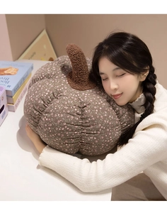 Floral pumpkin plush pillow held by a model in a cozy and warm home setting