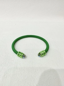 Detail eines mattgrünen Kabelarmbands mit gedrehter Textur und Kristall-Endkappen