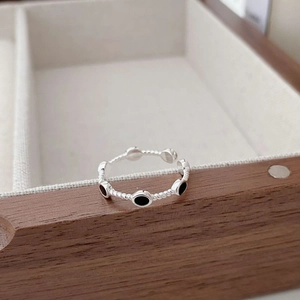 Macro detail of silver twisted rope ring with black oval enamel on a wooden display