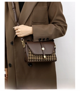 Detail of houndstock pattern fabric and brown leather patchwork on the crossbody bag