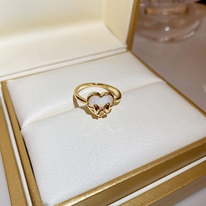 Macro shot of opal heart and gold bow ring displayed in a premium velvet jewelry box