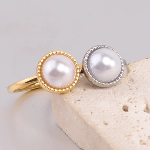 Detail of double pearl open ring with gold and silver finish on natural stone