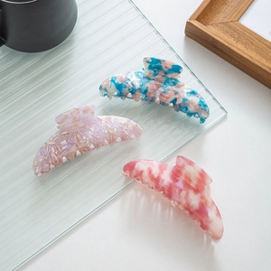 Close-up of three marble-patterned acetate hair claw clips with elegant crescent moon shapes